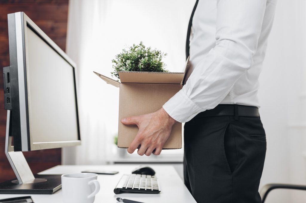 Dissapointed businessman clearing his desk after being let go. Represents the concept of severance pay.