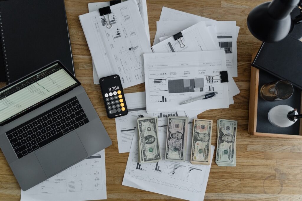 A payroll administrator's desk is covered in stacks of paperwork and money to represent laws like FLSA that govern payroll and wages.